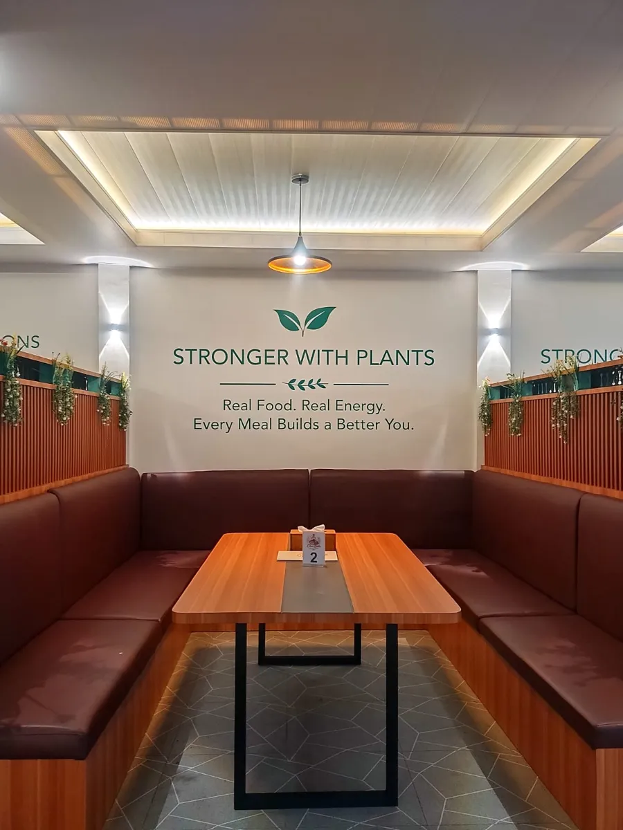 Booth seating under a Stronger with Plants wall sign