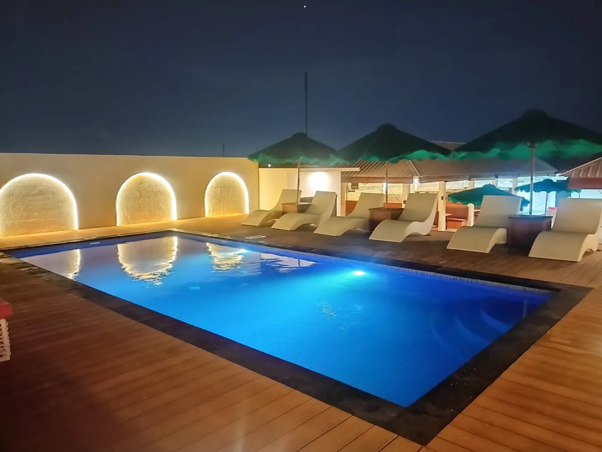 Rooftop pool with sun loungers at night